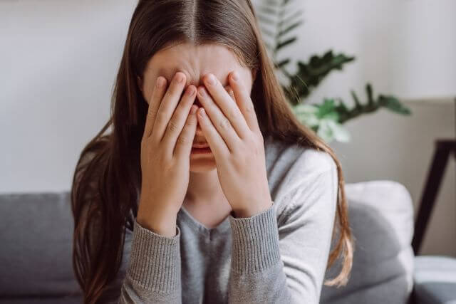 顔を抑える女性